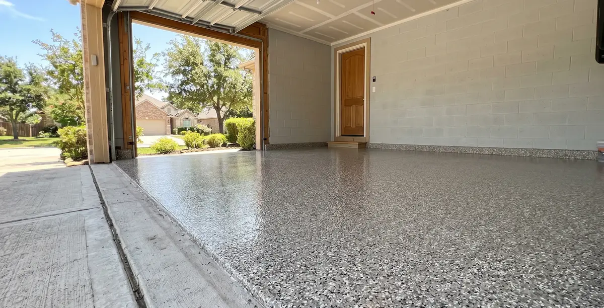 Covered porch with a speckled concrete floor, white wall, and open view to the yard.