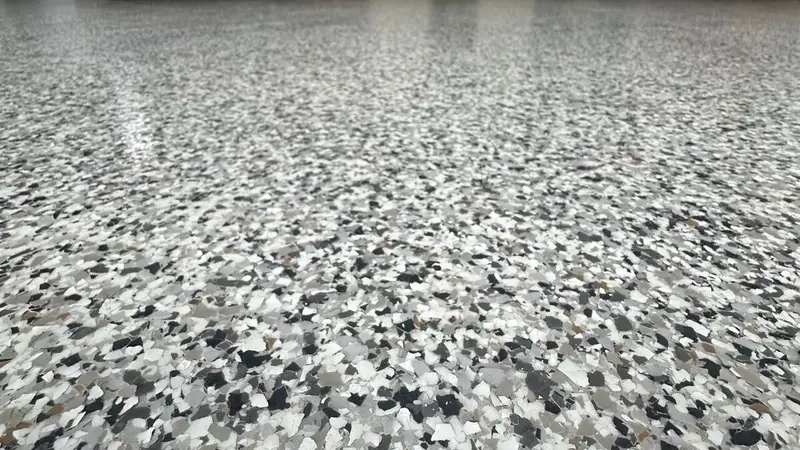 Close-up of a gray, white, and black flake epoxy floor finish