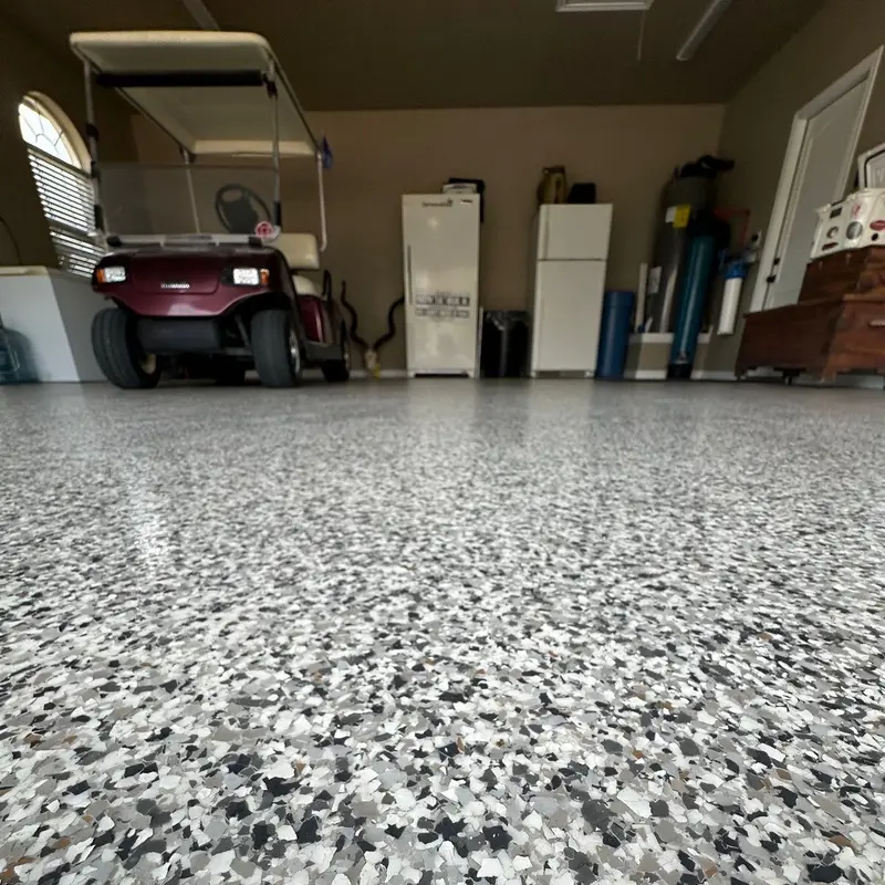 Close view of a gray flake epoxy garage floor next to a golf cart