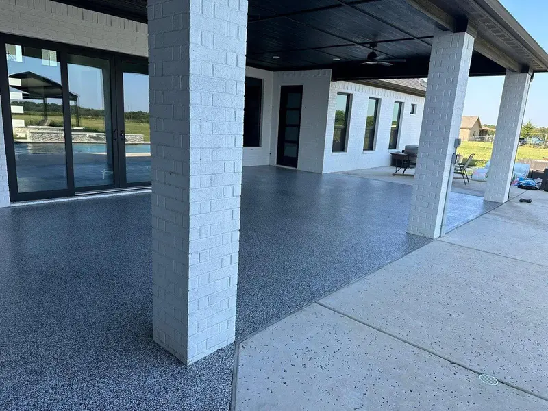 Covered patio with a gray flake coating and white brick columns