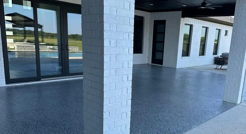 Covered patio with gray flake floor, white brick columns, and sliding doors to a pool